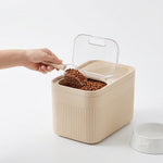 Measuring cup positioned beside the PAWZINA food storage container
