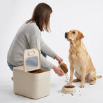 Included measuring cup shown scooping food from the PAWZINA storage container